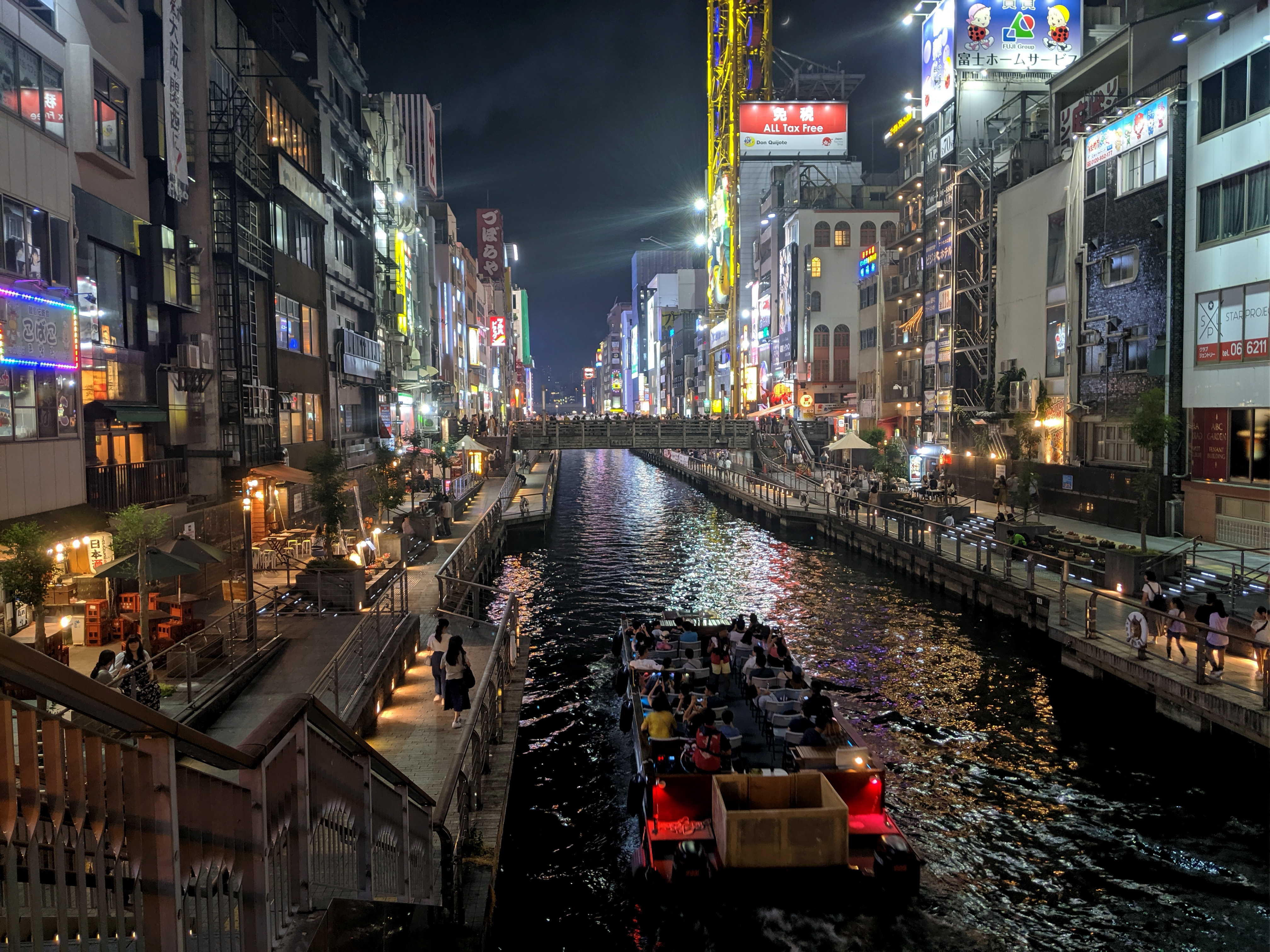 Sightseers travel down the Osaka canal at night near Dōtonbori: The Bizarre Bazaar